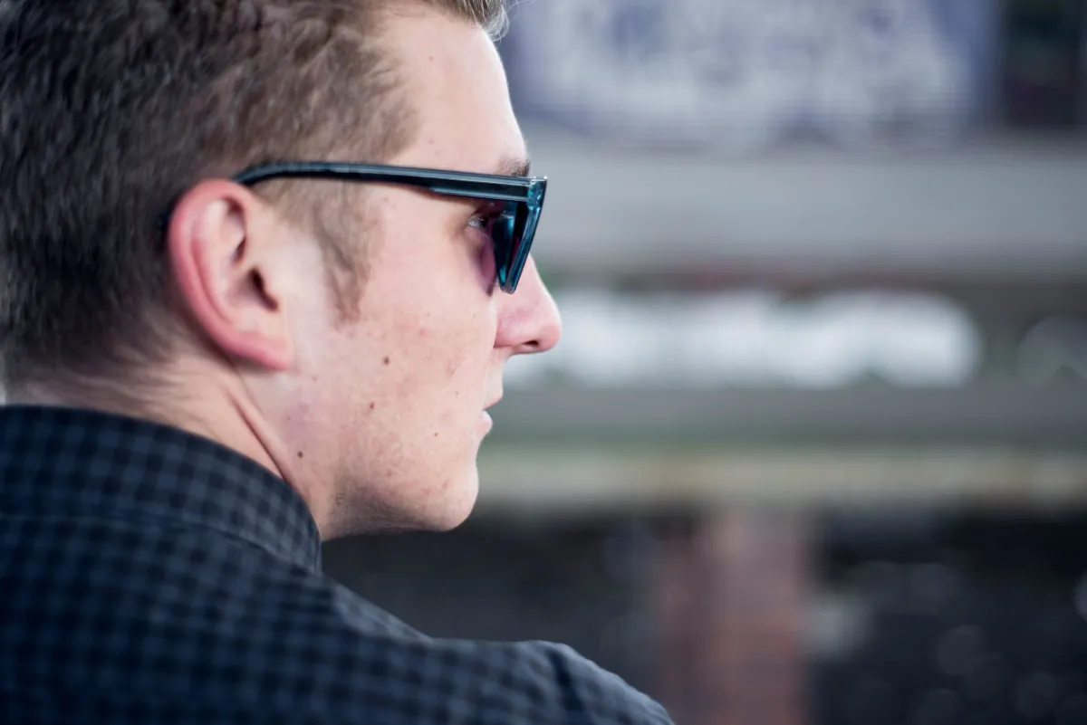 DJ EMC im Profil mit Sonnenbrille, Nahaufnahme vor unscharfem Hintergrund